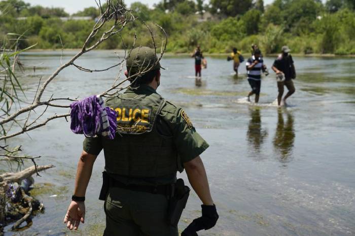 Un agente de la Patrulla Fronteriza de Estados Unidos observa a un grupo de migrantes cruzar el río Bravo para entregarse a las autoridades el 15 de junio de 2021, en Del Rio, Texas. (AP Foto/Eric Gay, archivo)