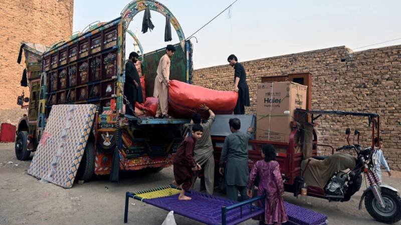 Miembros de una familia de refugiados afganos carga sus pertenencias en un camión para volver a Afganistán. Foto: AFP