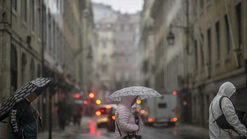 Unos peatones cruzan una calle de Lisboa capuital de Portugal bajo la lluvia, provocada por la tormenta Aline. Foto: AFP