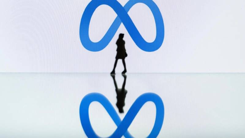 Foto tomada en Mulhouse, este de Francia, muestra la silueta de una mujer caminando cerca del logo de la gigante tecnológica Meta. Foto: AFP
